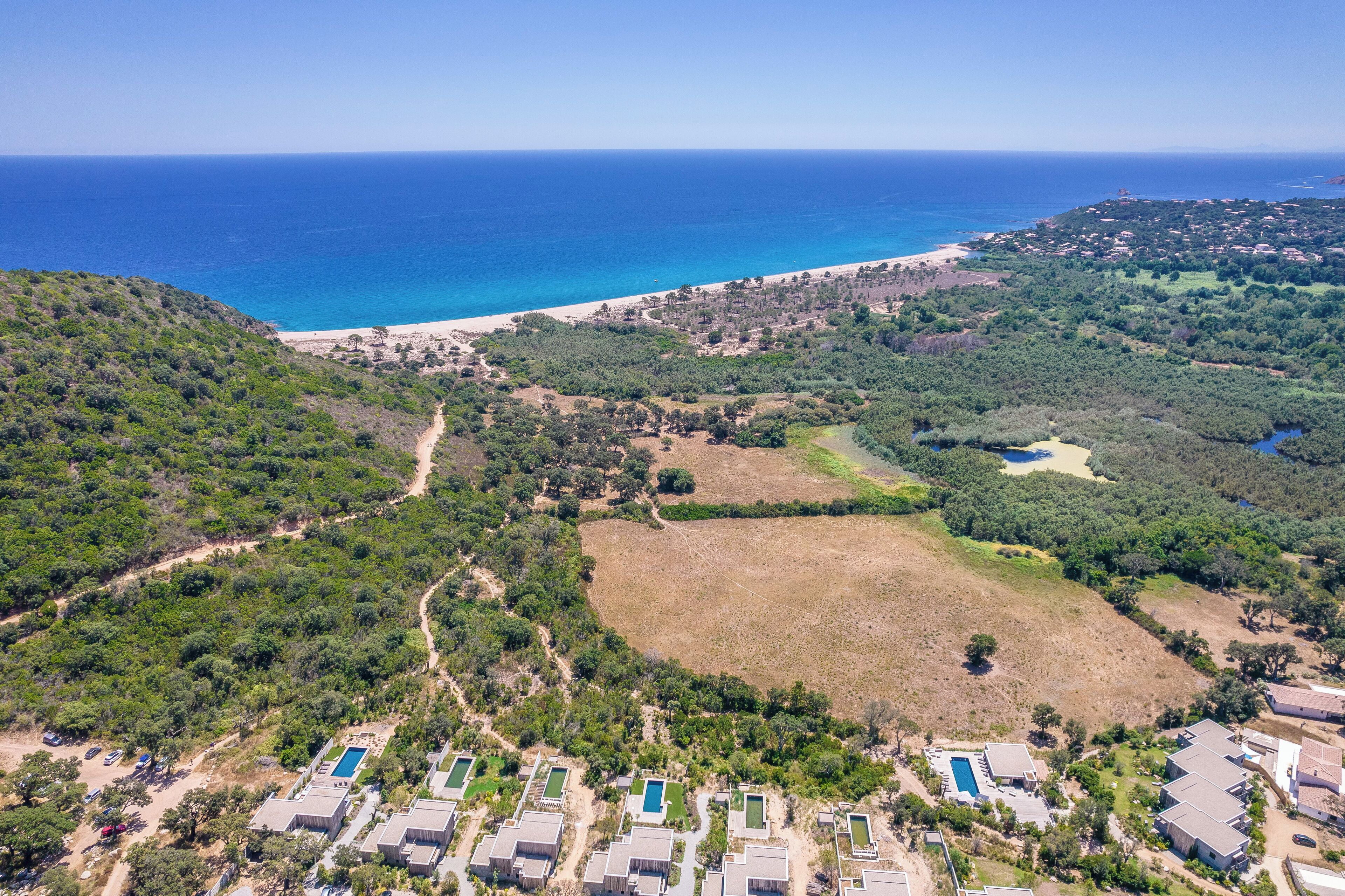 Luftaufnahme eines Küsteneigentums mit mehreren Pools, einem Strand und üppiger Vegetation.