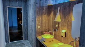 Une salle de bain moderne avec un mur en bois, un lavabo jaune et un miroir.