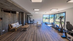 Une pièce spacieuse avec un plancher en bois, un banc, une chaise et du matériel d’exercice.