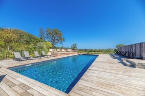Une piscine rectangulaire à l’eau d’un bleu cristallin, entourée d’une terrasse en bois.