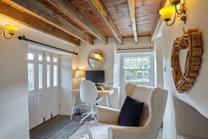 A room with a wooden ceiling, a desk with a computer, a chair, and a window with a view.