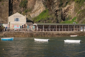 A coastal building named 'BOATHOUSE' with a dock and several boats.