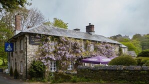 Un bâtiment en pierre avec une enseigne indiquant : « The Mill Accommodations, parking gratuit et bar ».
