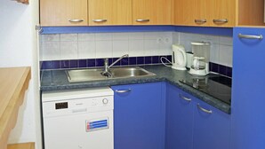 A compact kitchen with blue cabinets, a dishwasher, a sink, and a coffee maker. - Ski-in/ski-out apartment with indoor pool, close to amenities (Les Orres)