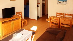 A cozy living room with a TV, wooden furniture, and a painting on the wall. - Ski-in/ski-out apartment with indoor pool, close to amenities (Les Orres)
