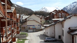 A mountain village with wooden buildings, a restaurant, and a car parked in the street. - Ski-in/ski-out apartment with indoor pool, close to amenities (Les Orres)