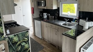 Cuina compacta amb microones, rentapelats i finestra amb vistes a vegetació.
