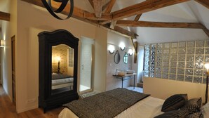 Een slaapkamer met een groot bed, een spiegel, een nachtkastje, een raam met uitzicht en een houten plafond.