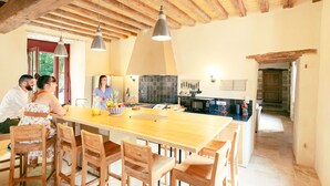 Een ruime keuken met houten balken, een groot eiland en moderne apparatuur.