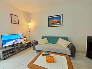 Ein Wohnzimmer mit Fernseher, einer Couch, einem Couchtisch und einem Kamin.