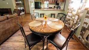Un coin repas comprenant une table ronde, quatre chaises et un vase orné d’un tournesol.