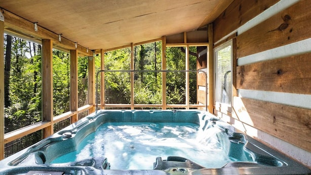 Un bain à remous dans un chalet en bois avec vue sur la forêt.