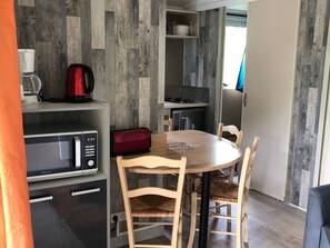 A compact kitchen with a microwave, toaster, and coffee maker. There is a round wooden table with four chairs.