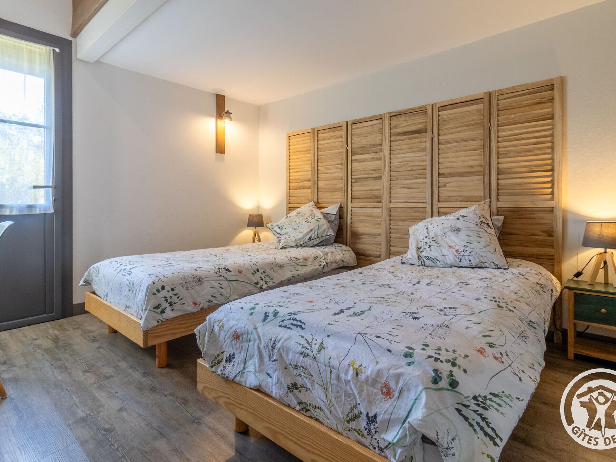 Ein Schlafzimmer mit zwei Holzbetten, jeweils mit floralem Bettzeug und Nachttischlampen.