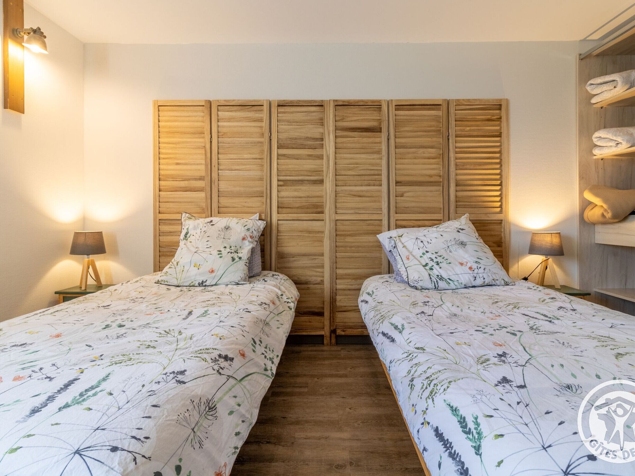 Ein Doppelzimmer mit zwei Betten, Holz-Kopfteilen und Nachttischlampen.