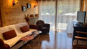 Ett mysigt rum med en väggpanel av trä, en soffa, en fåtölj, ett litet bord och en tv.