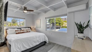 A bedroom with a bed, two windows, a ceiling fan, and a potted plant. - Bright Beach access retreat w/ AC (Laguna Beach)