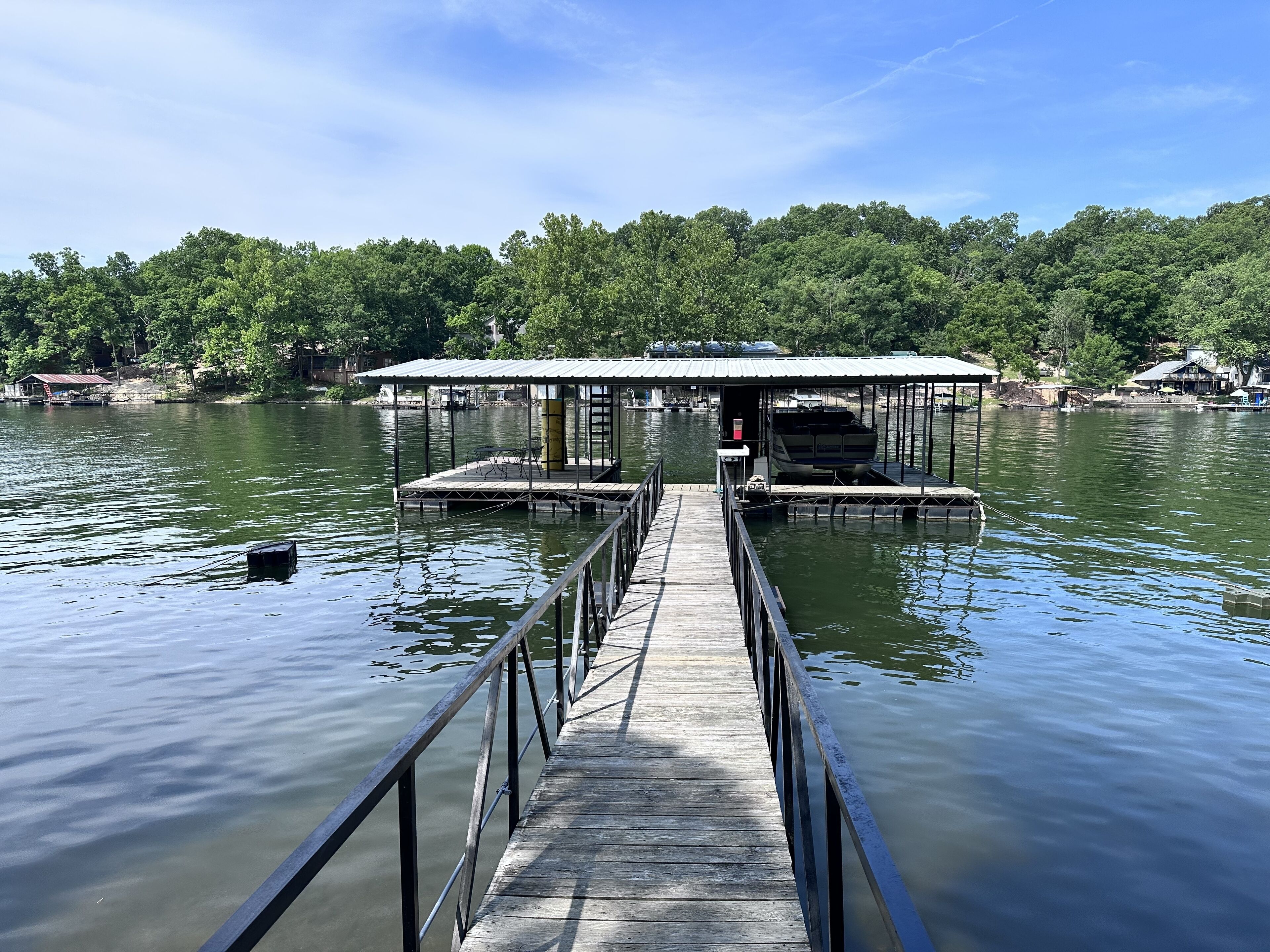 A wooden pier leading to a covered dock with a boat moored at the end.