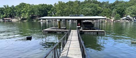 A wooden pier leading to a covered dock with a boat moored at the end.