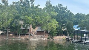 A lakeside property with a dock, a covered boat ramp, and a small building. - Updated Ozarks Lakefront Home-Lilly pad, kayaks, Private dock & boat ramp. (Sunrise Beach)