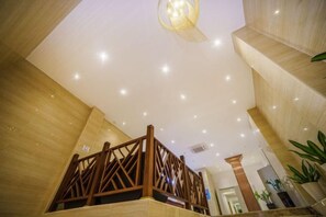 A hotel lobby with a wooden staircase, a chandelier, and a modern ceiling design. - Junchao Light Luxury Hotel (Zhuhai)