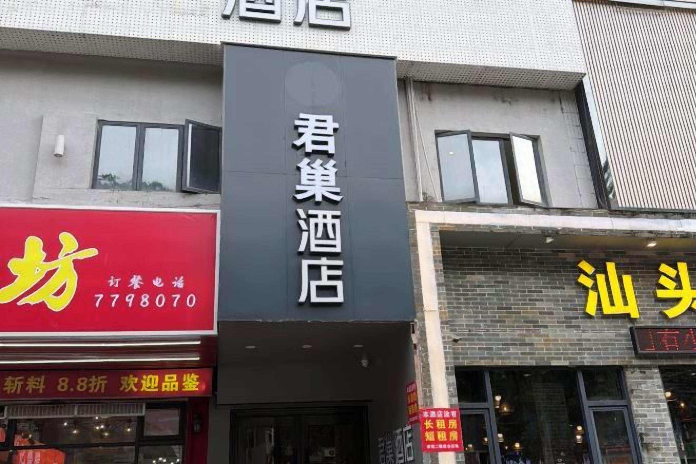 A hotel with a prominent sign and adjacent businesses.