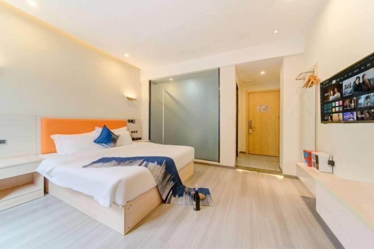 Una habitación de hotel moderna con una cama, un escritorio, un televisor y una puerta que da a otra habitación.