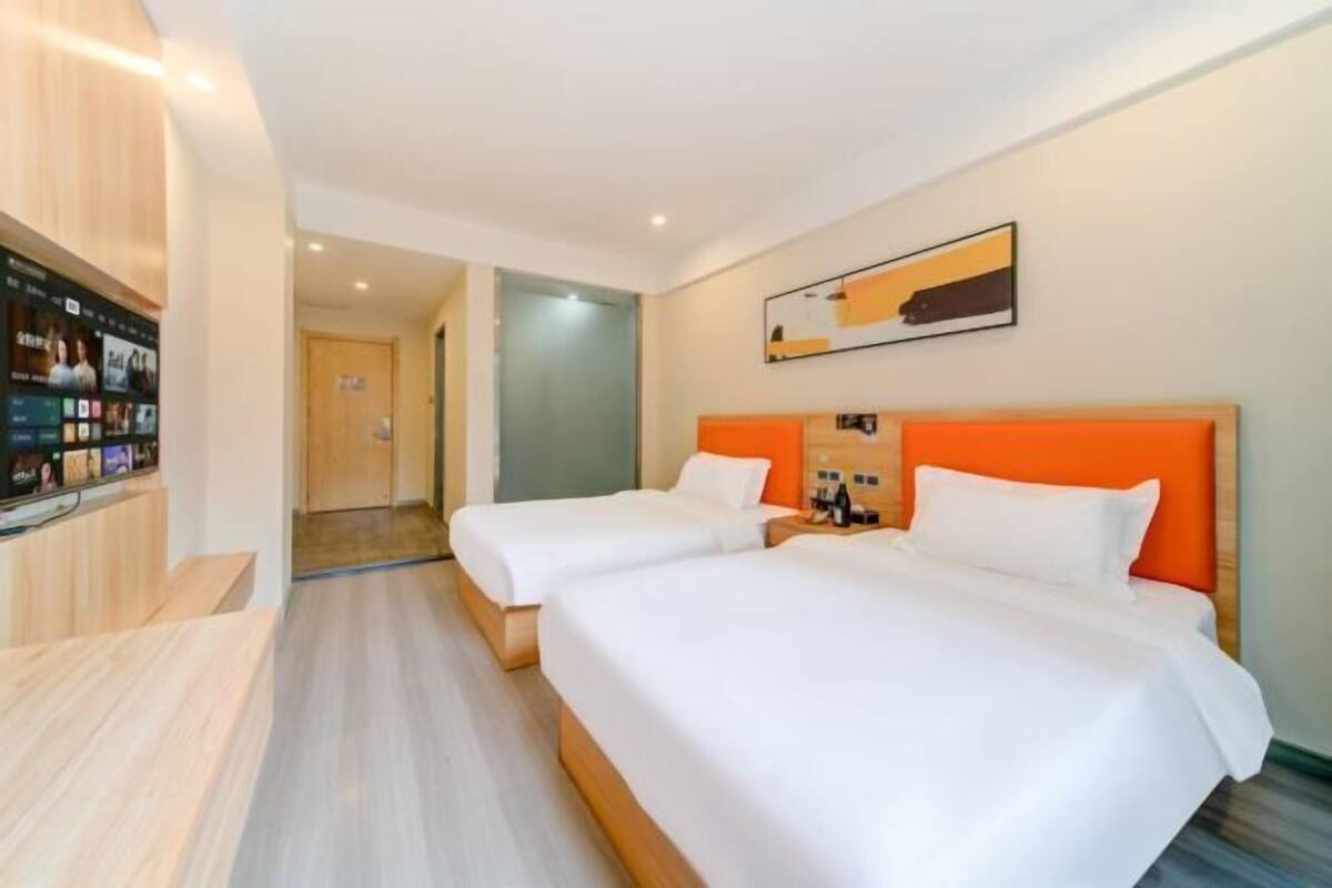 A hotel room with two beds, a TV, and a desk.