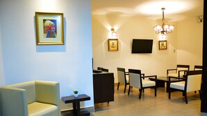A modern living room with a sofa, a small table with a plant, and a dining area with chairs and a table. - Hotel Alegria Nasca (Nazca)