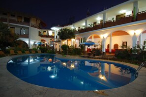A hotel with a swimming pool, outdoor seating, and multiple balconies.