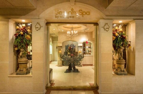 Enter Serenity Spa, where a grand archway welcomes you to a tranquil space featuring a large ornate mirror and beautiful flower arrangements.
