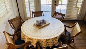 Une table ronde recouverte d’une nappe à motifs floraux, entourée de chaises en bois dotées d’assises rembourrées.