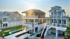 Un quartier résidentiel situé sur la côte, composé de plusieurs maisons à deux étages dotées de balcons, ainsi que d’une maison principale avec un porche ensoleillé, le tout sous un ciel dégagé.