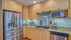 Una cocina con armarios de madera, electrodomésticos de acero inoxidable y encimera de granito.