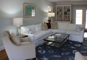 Relax in this stylish living room with a white sectional sofa, glass coffee table, and a cozy armchair.