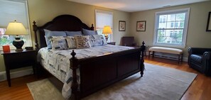 Relax in a serene bedroom with a large four-poster bed, adorned with a quilt and decorative pillows.