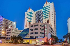 A modern hotel with a glass facade, multiple floors, and a visible restaurant named "Scooby's Ice Cream & Grill" at the ground level.