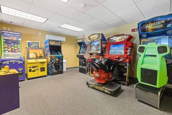 Una habitación con varios juegos de arcade, incluyendo un juego de pinzas, juegos de carreras y un juego de boxeo.