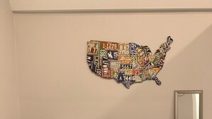 En sort sofa med et mønstret tæppe og et kort over USA hængt på væggen.