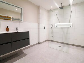 A modern bathroom with a glass-enclosed shower, a vanity with dark cabinets, and a mirror above the sink. - Carriage House (Macclesfield)