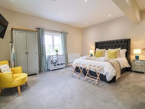 A bedroom with a bed, bedside tables, a chair, a wardrobe, and a window. - Carriage House (Macclesfield)