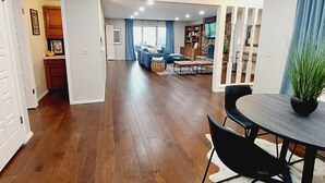 Amplia sala de estar con piso de madera, una mesa de comedor con sillas, un sofá y una chimenea.