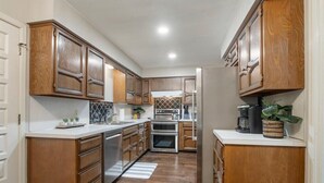 Una cocina moderna con armarios de madera, electrodomésticos de acero inoxidable y una isla central.