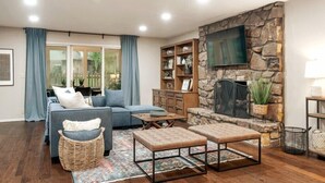 Un salón con chimenea de piedra, un sofá azul, una mesa de centro y una estantería.