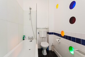 Kylpyhuoneessa on kylpyamme, wc ja suihku. Seinällä on värikkäitä, pyöreitä koristeita.