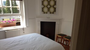 A bedroom with a large bed, a fireplace, and a view of the outside through a window. - Large Shoreditch 2/dbl bed Loft apt (London)
