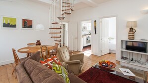 A spacious living room with a high ceiling, a spiral staircase, a dining area, and a kitchen. - Large Shoreditch 2/dbl bed Loft apt (London)