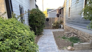 A paved pathway leading to a wooden gate, surrounded by greenery and a stone wall. - 1890 Graystone Cottage behind Historic Home short walk to Downtown & Whiskey Row (Prescott)