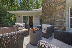 A patio area with wicker furniture, a stone wall, and a fire pit. - Union Pier Home Walking Distance To Beach With Hot Tub! (Union Pier)
