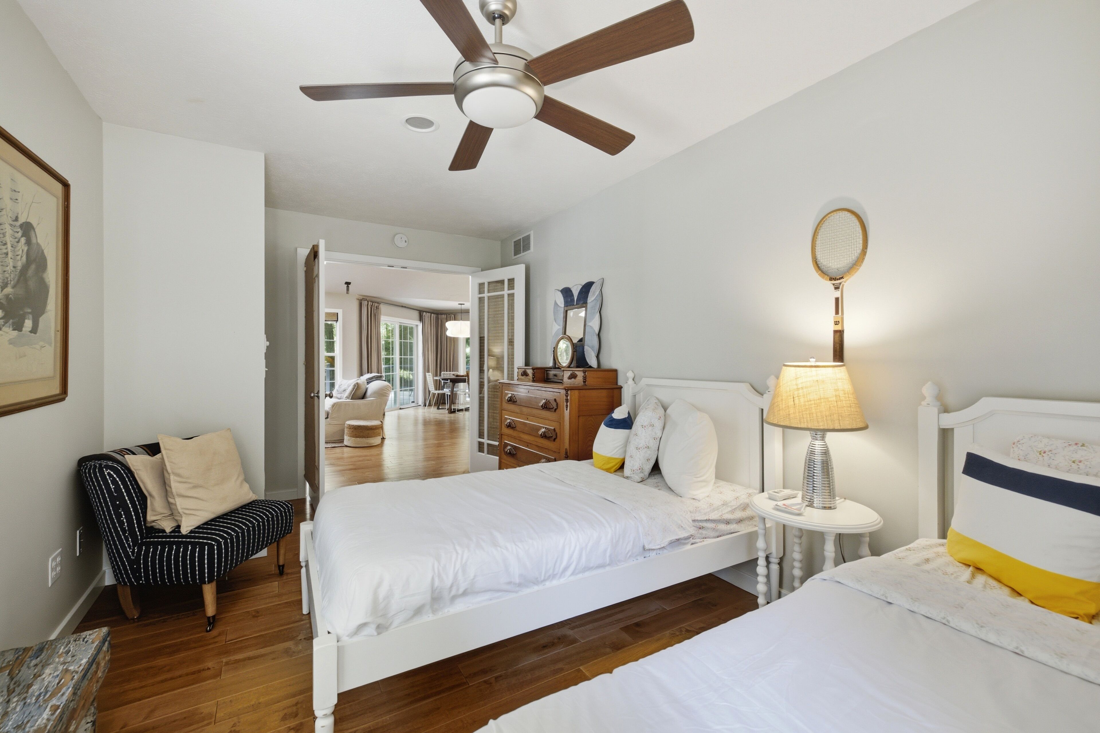 Quarto com cama, mesa de cabeceira, abajur e ventilador de teto.